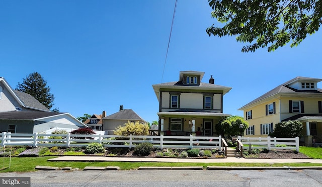 american foursquare style home with a porch, a fenced front yard, and a chimney