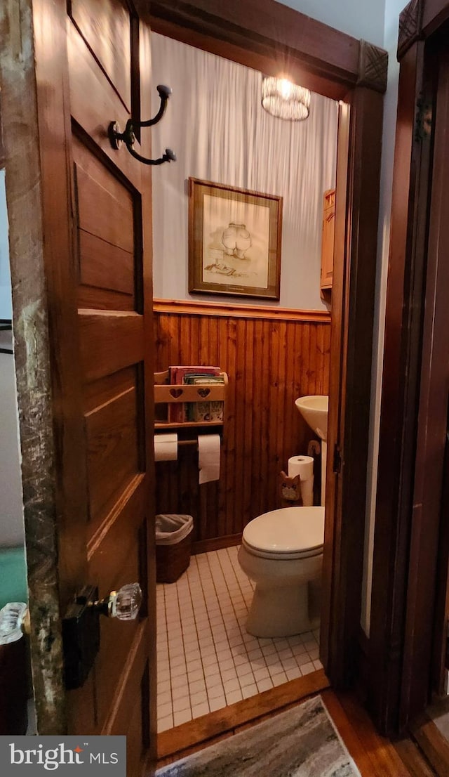 bathroom with toilet, wainscoting, wooden walls, and a chandelier