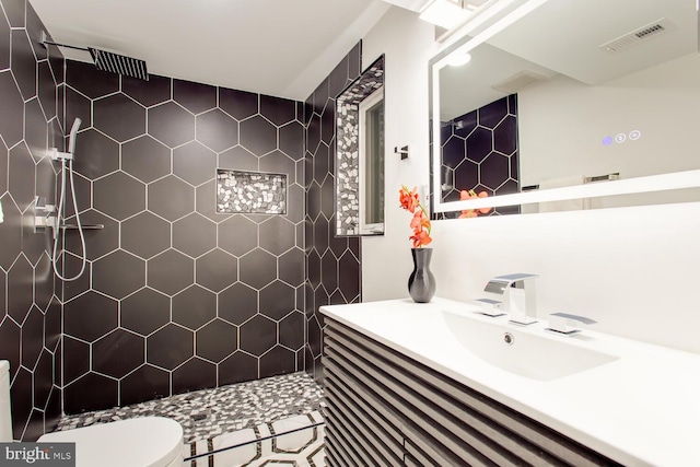 bathroom featuring tiled shower, vanity, and toilet