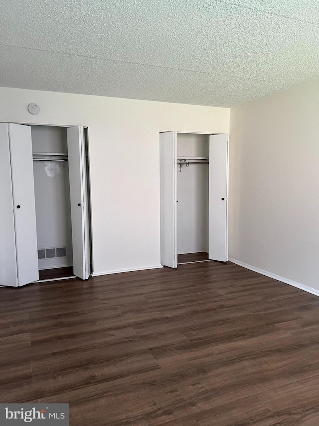 842 Putnam Blvd Unit 60A, Wallingford, PA 19086 - unfurnished bedroom featuring dark wood finished floors, two closets, and a textured ceiling