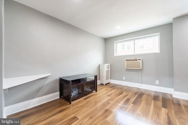 unfurnished room featuring a wall unit AC, wood finished floors, and baseboards