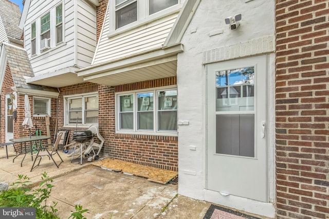 doorway to property featuring brick siding and a patio