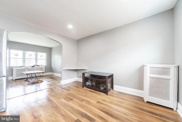 living room with arched walkways, wood finished floors, baseboards, and recessed lighting