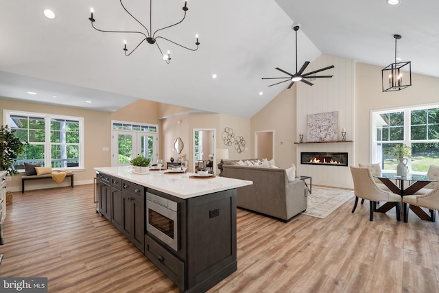 5570 Warren Dr, Huntingtown, MD 20639 - kitchen with high vaulted ceiling, stainless steel microwave, open floor plan, light countertops, and light wood-style floors