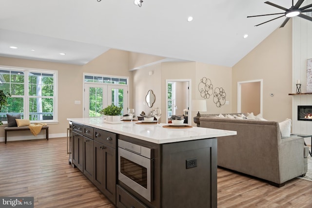 5570 Warren Dr, Huntingtown, MD 20639 - kitchen with light wood finished floors, stainless steel microwave, light countertops, open floor plan, and high vaulted ceiling