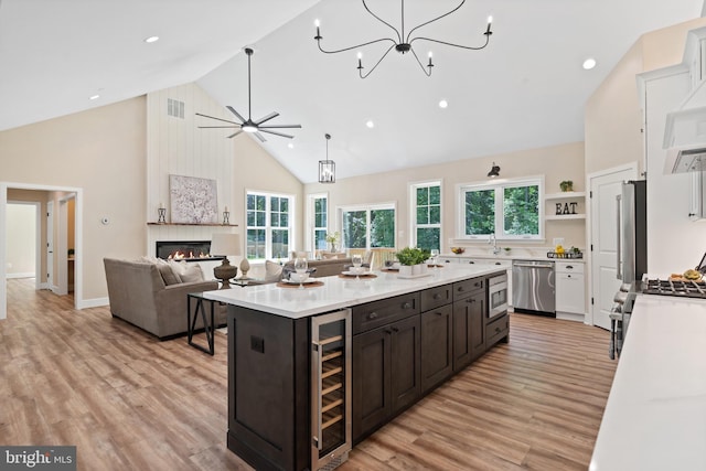 5570 Warren Dr, Huntingtown, MD 20639 - kitchen with stainless steel appliances, high vaulted ceiling, light countertops, light wood-style floors, and a fireplace