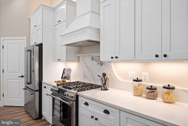 5570 Warren Dr, Huntingtown, MD 20639 - kitchen with appliances with stainless steel finishes, premium range hood, white cabinetry, wood finished floors, and decorative backsplash
