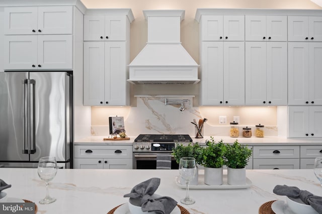 5570 Warren Dr, Huntingtown, MD 20639 - kitchen featuring stainless steel appliances, premium range hood, white cabinetry, and light stone countertops