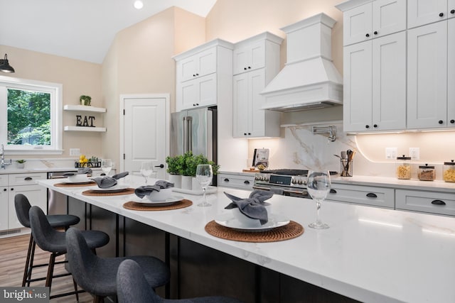5570 Warren Dr, Huntingtown, MD 20639 - kitchen featuring custom range hood, premium appliances, a kitchen bar, lofted ceiling, and white cabinetry