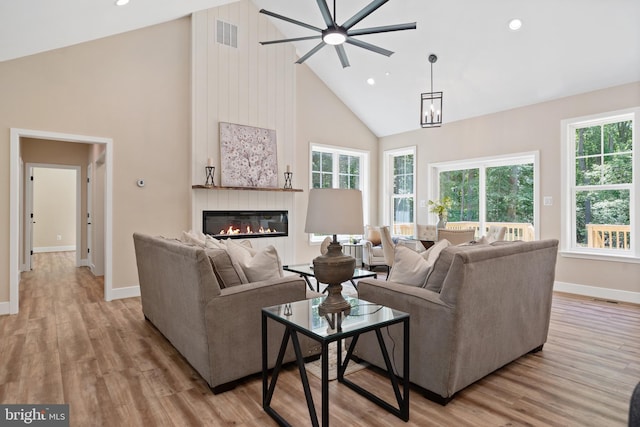 5570 Warren Dr, Huntingtown, MD 20639 - living area with high vaulted ceiling, a ceiling fan, a glass covered fireplace, baseboards, and light wood-style floors