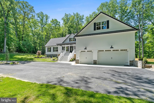 5570 Warren Dr, Huntingtown, MD 20639 - view of front of house with asphalt driveway, an attached garage, stairs, and a front lawn