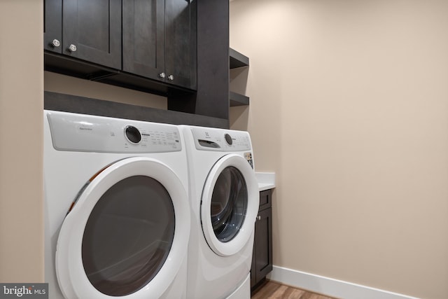 5570 Warren Dr, Huntingtown, MD 20639 - laundry area featuring independent washer and dryer, cabinet space, light wood-type flooring, and baseboards