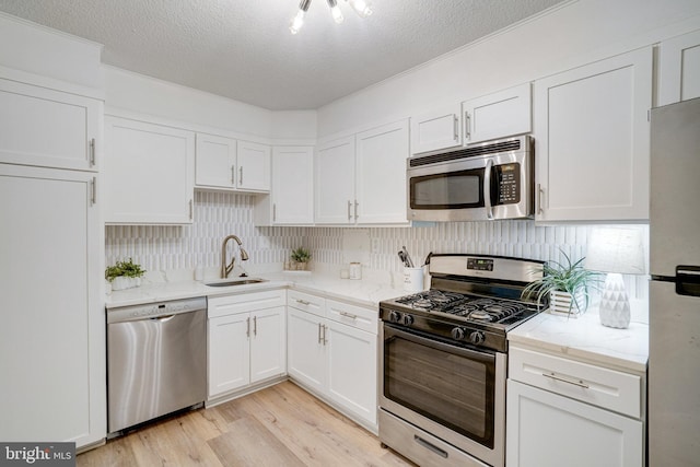 1300 Army Navy Dr Unit 124, Arlington, VA 22202 - kitchen featuring appliances with stainless steel finishes, a sink, white cabinets, light wood-style floors, and backsplash