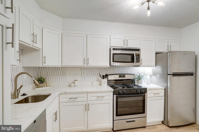 1300 Army Navy Dr Unit 124, Arlington, VA 22202 - kitchen with stainless steel appliances, a sink, white cabinetry, a textured ceiling, and light stone counters