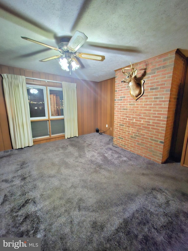 671 Fox Dr, Winchester, VA 22603 - carpeted empty room with a ceiling fan, a textured ceiling, wooden walls, and brick wall