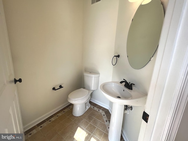 bathroom featuring baseboards, toilet, tile patterned flooring, and a sink