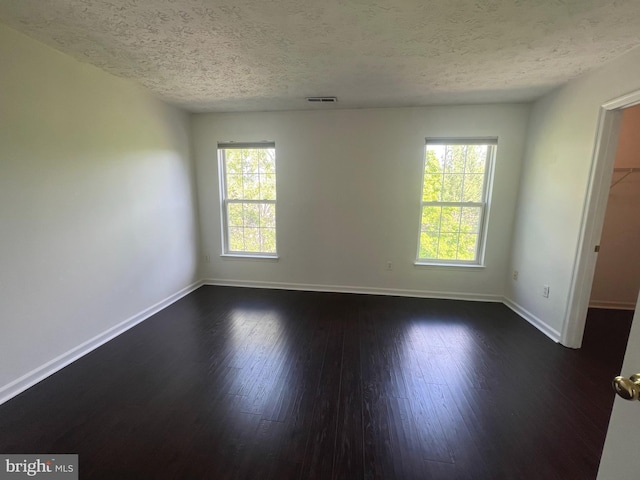 unfurnished room featuring a textured ceiling, baseboards, and dark wood-type flooring