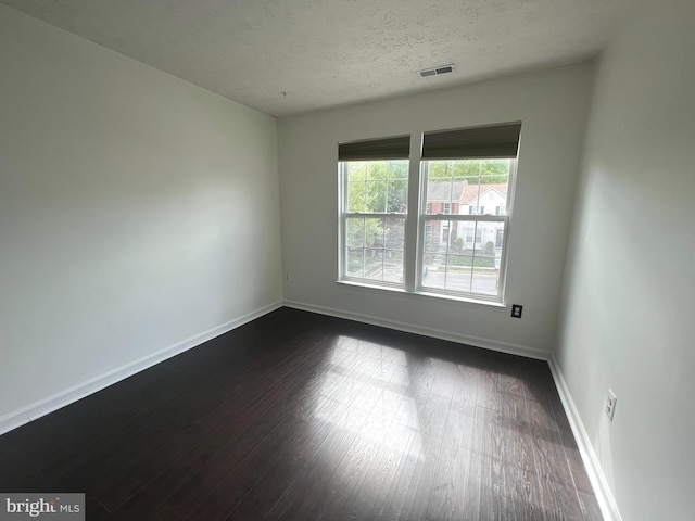 spare room with dark wood-style floors, baseboards, and a textured ceiling