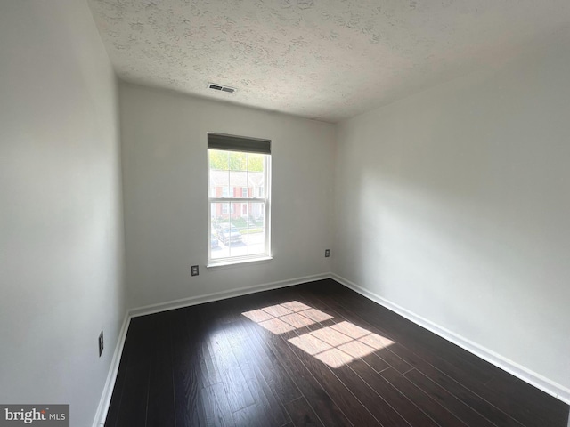 spare room with a textured ceiling, baseboards, and dark wood-style floors
