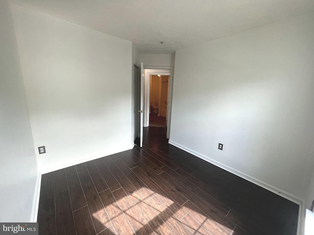 unfurnished room with dark wood finished floors and baseboards