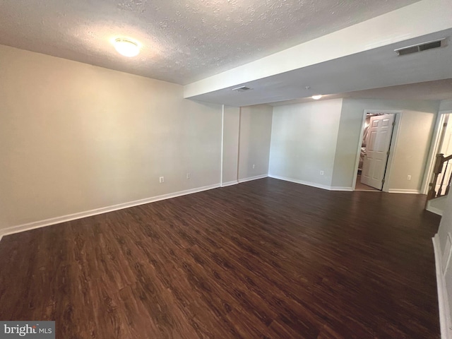 finished basement featuring dark wood-type flooring, a textured ceiling, and baseboards