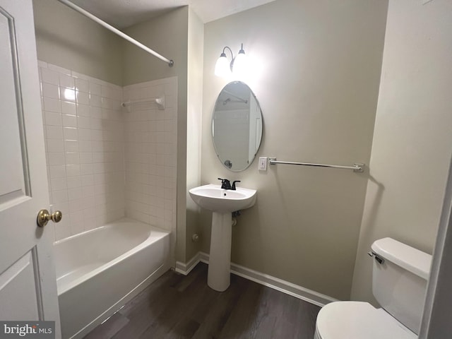 bathroom with wood finished floors, toilet, shower / tub combination, and baseboards
