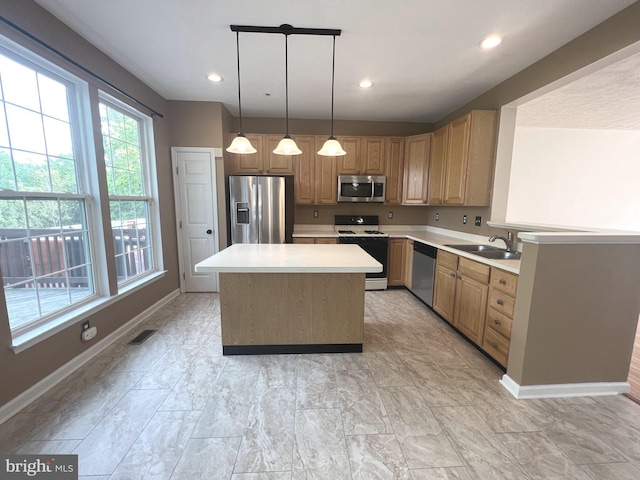 kitchen featuring appliances with stainless steel finishes, a sink, light countertops, baseboards, and a kitchen island