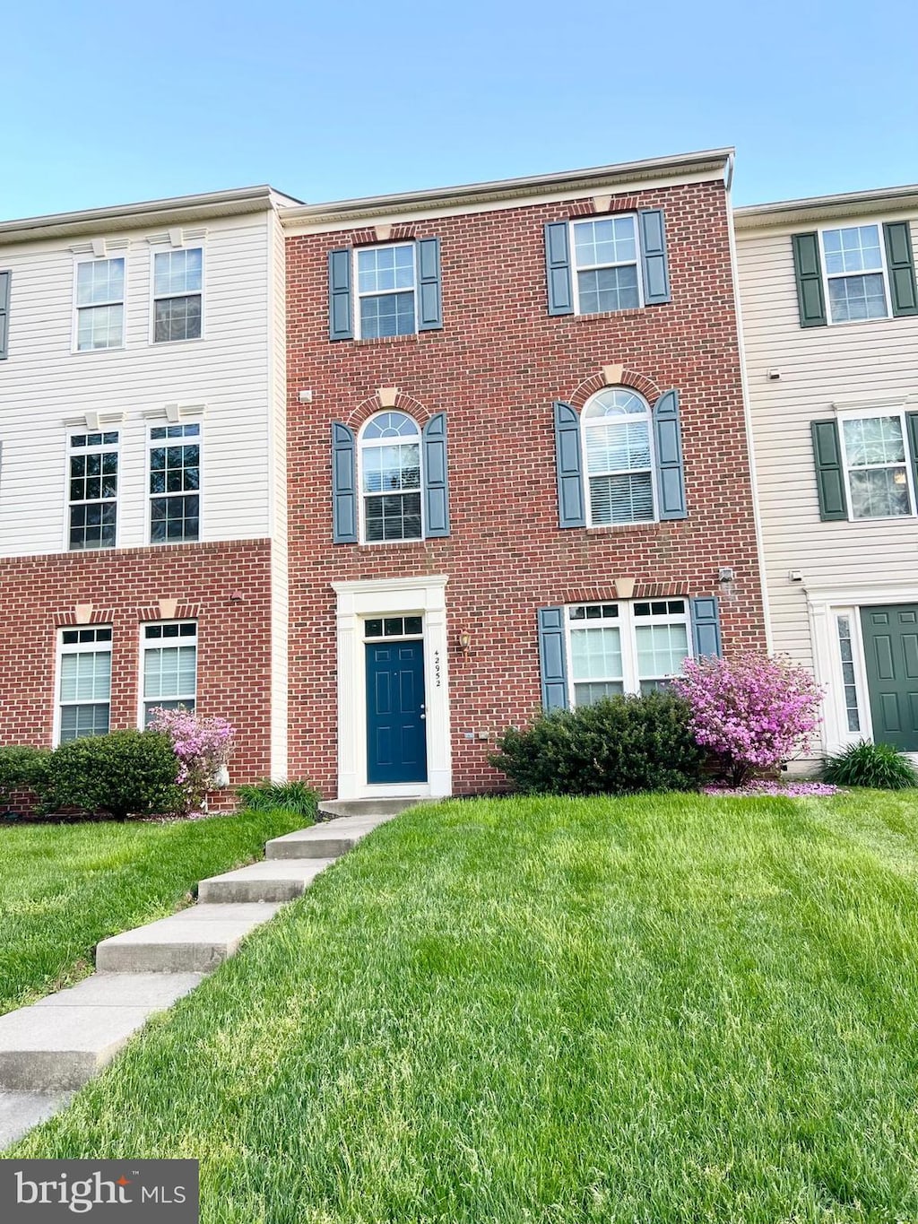 multi unit property with brick siding and a front lawn