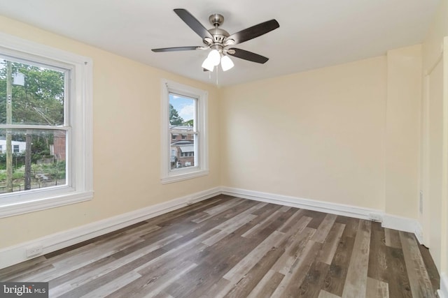 unfurnished room with plenty of natural light, wood finished floors, and baseboards