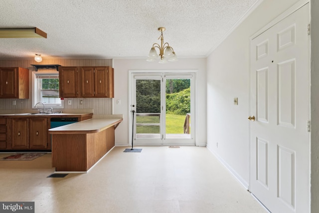 339 Gray Dr, Lusby, MD 20657 - kitchen with a textured ceiling, brown cabinets, ornamental molding, a peninsula, and a chandelier