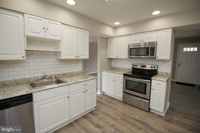 kitchen featuring appliances with stainless steel finishes, a sink, light wood-style floors, open shelves, and recessed lighting