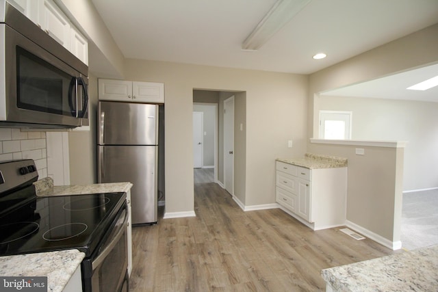 kitchen with stainless steel appliances, light wood-style flooring, white cabinets, light stone countertops, and recessed lighting