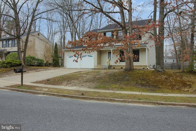 traditional home featuring covered porch, concrete driveway, fence, and an attached garage