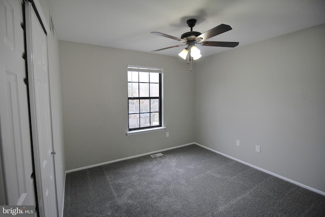 carpeted spare room with a ceiling fan and baseboards