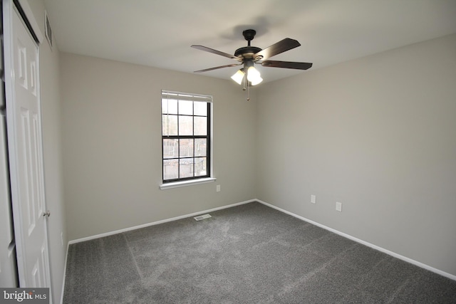 spare room featuring a ceiling fan, dark colored carpet, and baseboards