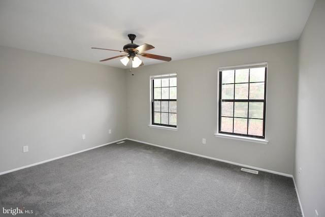 empty room featuring ceiling fan, baseboards, and dark colored carpet