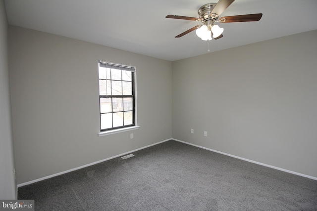 unfurnished room with a ceiling fan, baseboards, and dark carpet