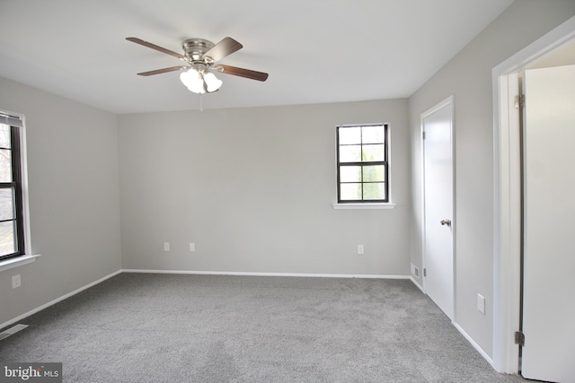 carpeted spare room with a ceiling fan and baseboards