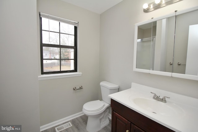 bathroom featuring toilet, vanity, wood finished floors, and baseboards