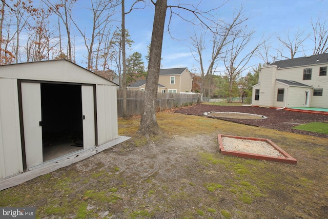 view of yard featuring fence, a shed, and an outbuilding