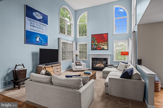 115 Hartefeld Dr, Avondale, PA 19311 - living room featuring wood finished floors, a towering ceiling, a fireplace with flush hearth, and baseboards