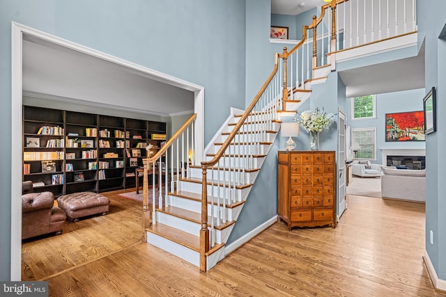 115 Hartefeld Dr, Avondale, PA 19311 - staircase featuring wood finished floors, a towering ceiling, a glass covered fireplace, and baseboards