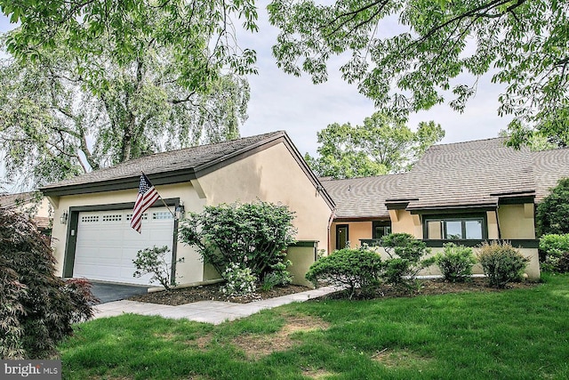 view of front of home featuring stucco siding, a garage, a front lawn, and asphalt driveway