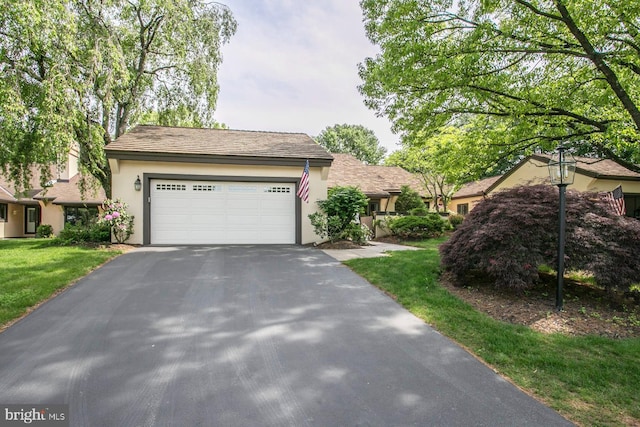 ranch-style home with asphalt driveway, stucco siding, a garage, and a front yard
