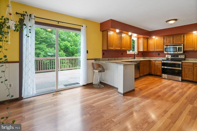 101 George St, Taneytown, MD 21787 - kitchen with stainless steel appliances, a peninsula, light wood-style flooring, and brown cabinets
