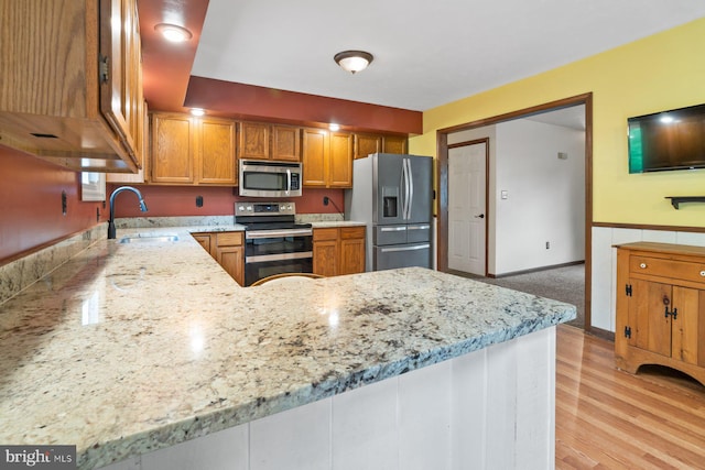 101 George St, Taneytown, MD 21787 - kitchen with stainless steel appliances, a sink, light stone counters, light wood-style flooring, and a peninsula