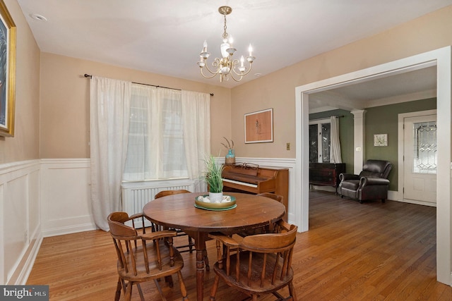759 Avenue F, Langhorne, PA 19047 - dining room featuring light wood-style flooring, a wainscoted wall, a chandelier, a decorative wall, and ornate columns