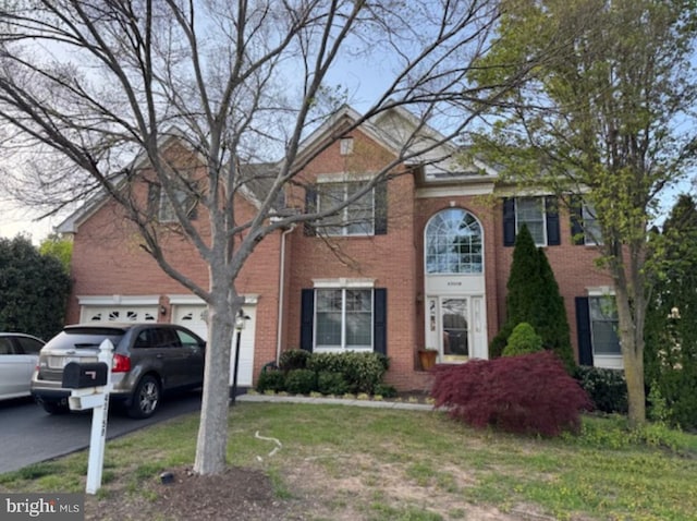 view of front of house featuring asphalt driveway, brick siding, and a garage
