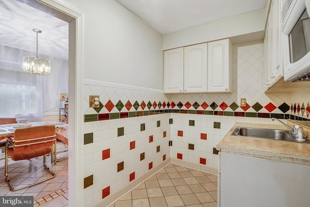 102 S Glebe Rd S, Arlington, VA 22204 - kitchen featuring light tile patterned flooring, a sink, a chandelier, white cabinets, and tile walls