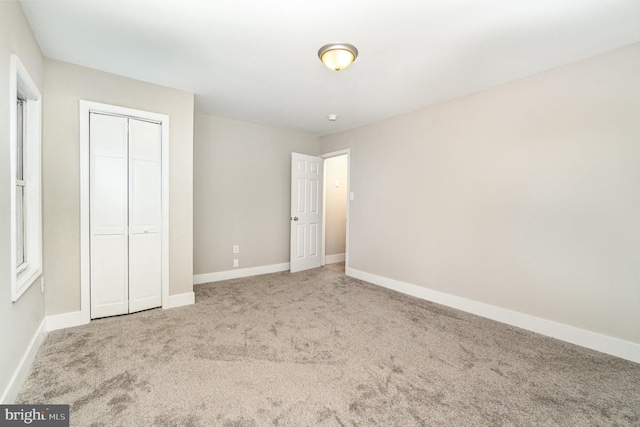 unfurnished bedroom with carpet flooring, baseboards, and a closet